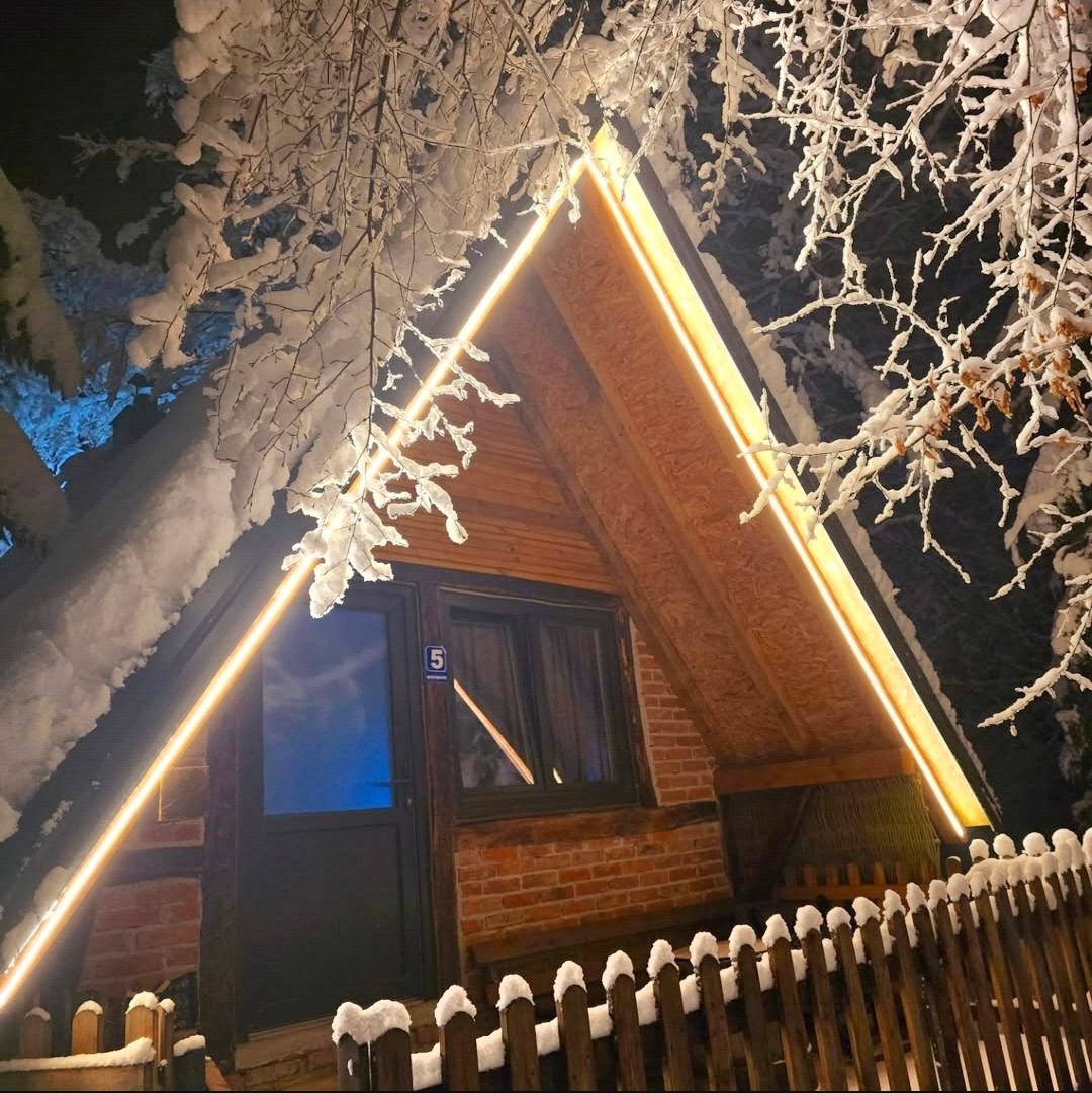 Drvena kućica s toplom rasvjetom pod snijegom